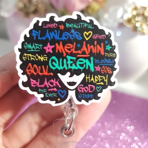 May include: A black and white graphic of a woman's afro with colorful text that reads "Loved Beautiful Flawless Melanin Soul Queen Black For Ever God Is Dope Happy Gifted Pure Blessed Sis". The graphic is attached to a clear plastic retractable badge holder.