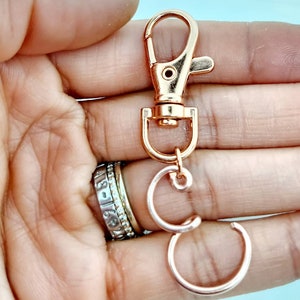 May include: Rose gold key chain with a lobster clasp and two connected rings.