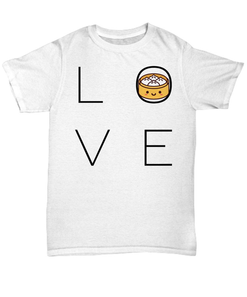 May include: White t-shirt with the word "LOVE" in black block letters. The "O" is replaced with a cartoon image of a dumpling in a bamboo steamer basket with a smiling face. A fun, food-themed graphic tee.