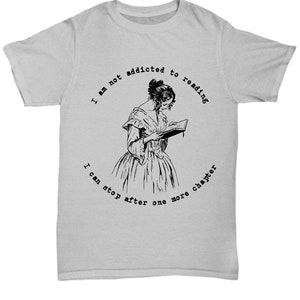 Peut inclure: T-shirt gris clair avec une illustration en noir et blanc d'une femme lisant un livre. Le texte autour de l'image dit : "Je ne suis pas accro &agrave; la lecture, je peux m'arr&ecirc;ter apr&egrave;s un autre chapitre."