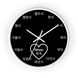 Könnte beinhalten: Eine schwarz-weiße Uhr mit einem weißen Herzen in der Mitte. Das Herz enthält das Wort "Korea" und das koreanische Wort für "Korea". Das Zifferblatt der Uhr hat die koreanischen Wörter für die Stunden 1 bis 12, die um den Rand herum geschrieben sind.