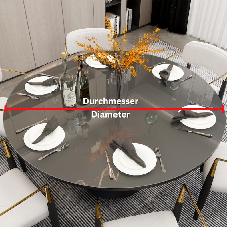 May include: A round glass table top with a dark gray finish. The table is set with white plates, silverware, and napkins. A vase with orange flowers sits in the center of the table. The text "Durchmesser" and "Diameter" are written on the table top.