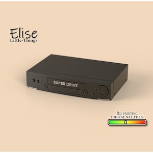 Puede incluir: Un reproductor VHS negro con el texto "SUPER DRIVE" en la parte delantera. Archivos STL digitales para impresión 3D.
