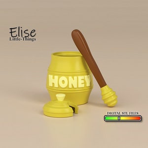 May include: A yellow honey pot with a brown wooden dipper. The pot has the word "HONEY" printed on it in white letters. The lid is off and sitting next to the pot. The dipper is resting on the table next to the pot.