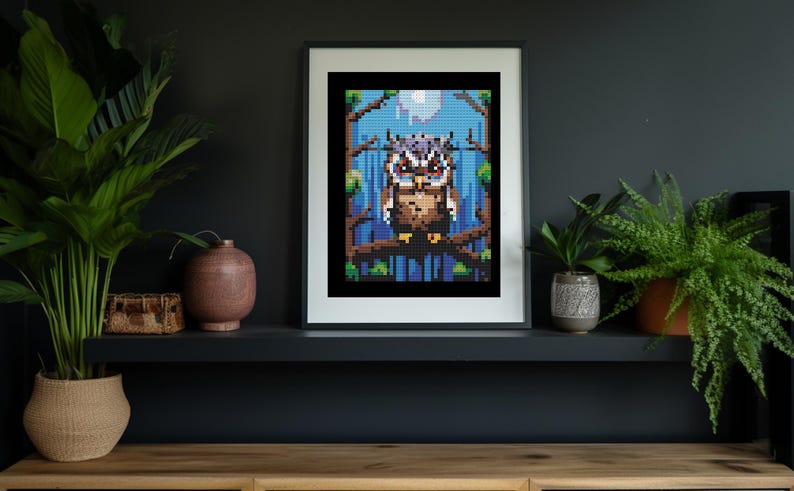May include: A framed pixel art print of an owl perched on a branch in a forest setting. The owl has brown and gray feathers and yellow eyes. The background is a blue and green gradient with a white moon.