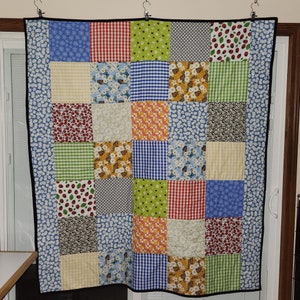 May include: A patchwork quilt with a variety of floral and geometric patterns in shades of red, blue, green, yellow, and white.