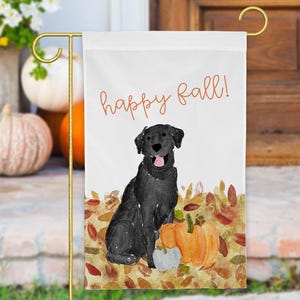 May include: A rectangular garden flag featuring a watercolor illustration of a black Labrador retriever sitting among autumn leaves and pumpkins. The text "happy fall!" is printed in orange cursive script at the top of the white background.