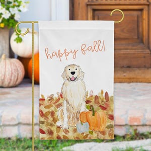 Pode incluir: Uma bandeira de jardim branca com uma ilustra&ccedil;&atilde;o em aguarela de um golden retriever sentado num monte de folhas de outono ao lado de uma ab&oacute;bora laranja. O texto "happy fall!" est&aacute; escrito em cursivo laranja acima do c&atilde;o.