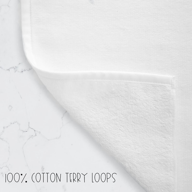 May include: A white towel featuring a folded corner that reveals the texture of the fabric. The text 100% COTTON TERRY LOOPS is printed at the bottom of the image, highlighting the material composition of the textile product.