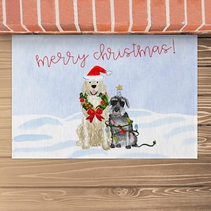 Könnte beinhalten: Eine weihnachtliche Fußmatte mit einem Golden Retriever, der einen Weihnachtsmann-Hut und einen Kranz trägt, und einem Zwergschnauzer, der einen Weihnachtsbaum mit Lichtern trägt. Die Fußmatte hat einen blauen Hintergrund mit weißem Schnee und den Text "merry christmas!" in Rot.