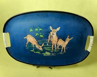 May include: A blue oval serving tray with black trim and white handles. The tray features a painted scene of three deer in a forest setting.