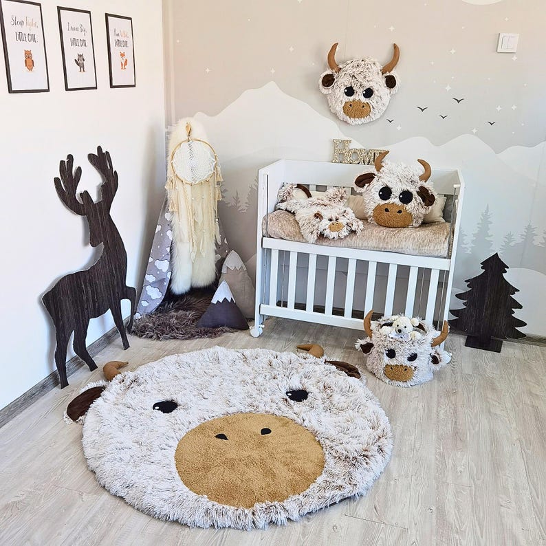 Round Highland Cow nursery rug crafted from ultra-soft Shaggy Minky fleece in light cream and warm tan tones, featuring plush 3D ears and horns, a large textured brown snout, and expressive black felt eyes. Measuring approx. 45 inches, this large decorative rug adds warmth, texture, and playfulness to any baby or toddler room. Lightweight and padded, it’s ideal for gentle play, Montessori corners, or as a cozy statement piece in Scandi-boho nurseries.