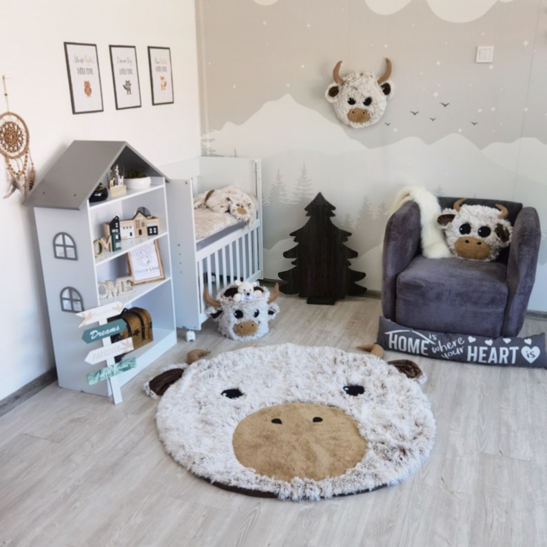 Complete nursery setup with Highland cow plush pillow, matching large rug, and wall decor in a beautifully coordinated design, perfect for modern children's rooms and unique baby shower gifts.