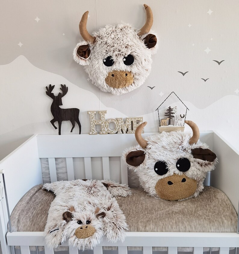 Cozy Highland cow plush pillow displayed in a nursery setting with coordinated decor items like a wall head and lovey, all available for purchase to create a harmonious kids' room theme.