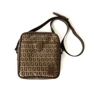 May include: A brown leather shoulder bag with a brown and black FF monogram pattern. The bag has a flap closure and a single adjustable strap.