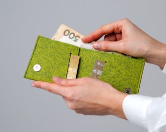 May include: A lime green felt wallet with a magnetic snap closure. The wallet is open, revealing a 500 Ukrainian hryvnia bill and two credit cards. The wallet is held by two hands.