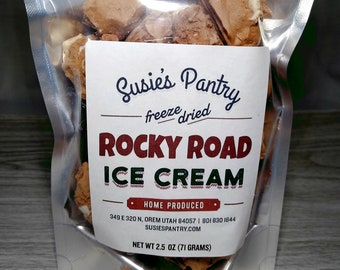 May include: A clear plastic bag filled with freeze-dried Rocky Road ice cream. The bag has a white label with the text "Susie's Pantry freeze dried Rocky Road Ice Cream Home Produced 349 E 320 N, OREM UTAH 84057 | 801 830 1644 SUSIESPANTRY.COM NET WT 2.5 OZ (71 GRAMS)"