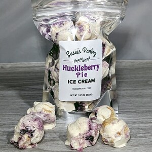 K&ouml;nnte beinhalten: Ein durchsichtiger Plastikbeutel gef&uuml;llt mit gefriergetrockneten Huckleberry-Pie-Eiscreme-St&uuml;cken. Der Beutel tr&auml;gt ein Etikett mit der Aufschrift "Susies Pantry freeze dried Huckleberry Pie ICE CREAM SUSIESPANTRY.COM NET WT 1 OZ (28 GRAMS)".