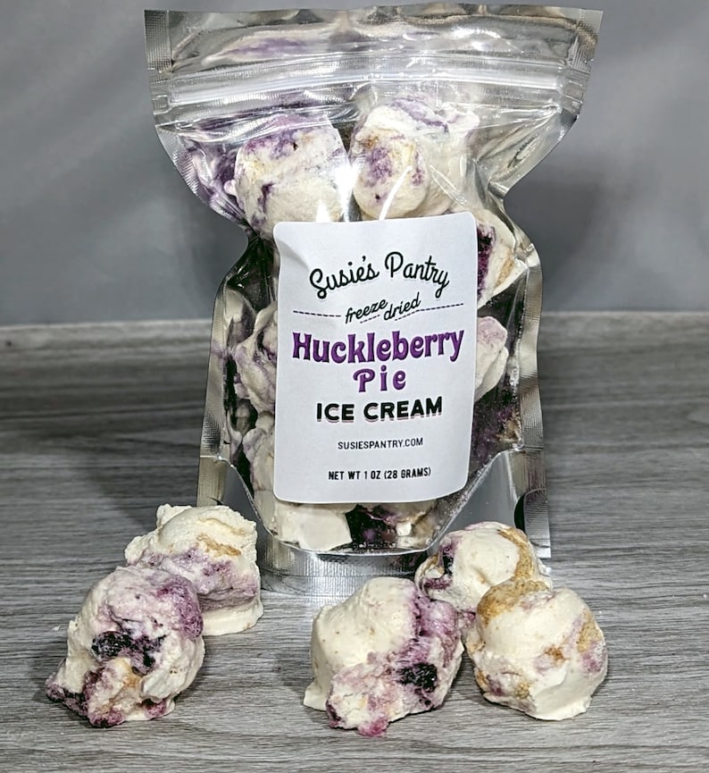 K&ouml;nnte beinhalten: Ein durchsichtiger Plastikbeutel gef&uuml;llt mit gefriergetrockneten Huckleberry-Pie-Eiscreme-St&uuml;cken. Der Beutel tr&auml;gt ein Etikett mit der Aufschrift "Susies Pantry freeze dried Huckleberry Pie ICE CREAM SUSIESPANTRY.COM NET WT 1 OZ (28 GRAMS)".