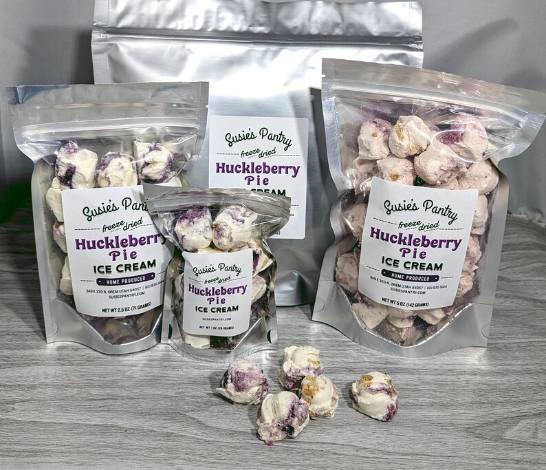K&ouml;nnte beinhalten: Drei durchsichtige Plastikt&uuml;ten gef&uuml;llt mit gefriergetrockneter Heidelbeer-Kuchen-Eiscreme. Die Beutel sind mit "Susie's Pantry Freeze Dried Huckleberry Pie Ice Cream" beschriftet.