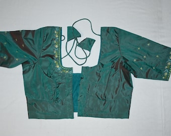 May include: Teal blouse with short sleeves. The blouse has a sheen and is decorated with embroidered floral patterns in shades of blue, green, and gold along the sleeve edges and neckline. The blouse is open in the front and has a tie closure.