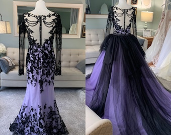 May include: A long-sleeved, black lace wedding dress with a purple ombre skirt. The dress has a fitted bodice and a flowing skirt. The lace is intricate and delicate. The dress is perfect for a gothic wedding.
