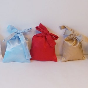 Peut inclure: Assortiment de neuf petits sacs en satin à cordon de serrage de différentes couleurs, dont blanc, bleu clair, rouge, beige, bleu marine et rose.