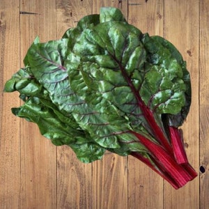May include: A bunch of fresh, green Swiss chard with red stems. The leaves are large and have a deep green color. The stems are bright red and are bundled together.