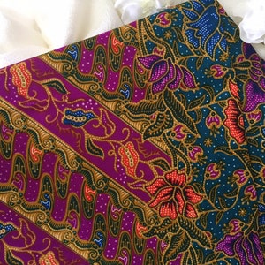 May include: Purple and teal fabric with a repeating floral pattern. The pattern features gold, red, blue, and white accents.