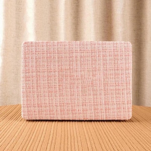 May include: A rectangular cushion featuring a textured, woven fabric in a soft salmon pink hue. The material displays a distinct grid-like pattern created by intersecting vertical and horizontal threads, resulting in a subtle, multi-tonal appearance.