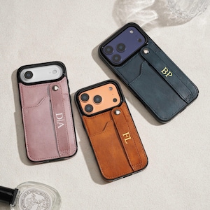 Puede incluir: Tres fundas de teléfono de cuero en rosa, marrón y verde azulado. Cada funda tiene una ranura para tarjetas y una correa de mano con iniciales. La funda rosa tiene "DIA", la marrón "FL" y la verde azulado "BP" en letras doradas.