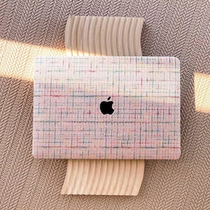 Op de afbeelding: Een laptop met een roze en wit geruit ontwerp. De laptop heeft een Apple-logo op de deksel.