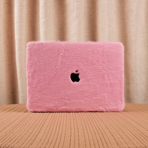 May include: A pink fuzzy laptop case with the Apple logo in the center.