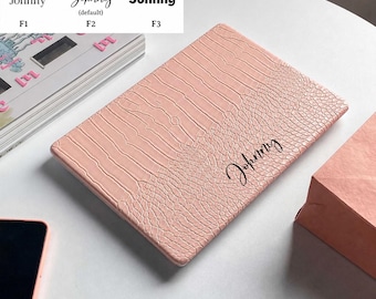 May include: A rectangular light pink tablet case with a textured crocodile skin pattern. The case features the name Johnny printed in a black cursive script font. A personalization guide at the top shows three font options labeled F1, F2, and F3.