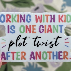 May include: A white sticker with colorful text that reads "Working with kids is one giant plot twist after another."