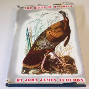 May include: The cover of a book titled "The Birds of America" by John James Audubon. The cover features a colourful illustration of a wild turkey in a natural setting.