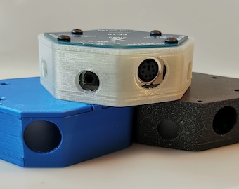 May include: Three hexagonal electronic devices in blue, white, and black. Each device has a circular opening and a connector port. The white device is on top, with a circuit board visible. The devices are stacked on top of each other.