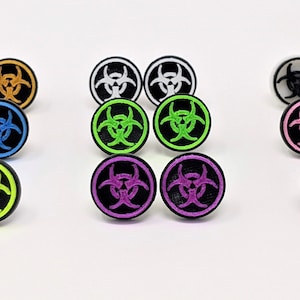 May include: A set of 10 pairs of earrings featuring a biohazard symbol in various colors, including green, purple, pink, blue, white, and black.