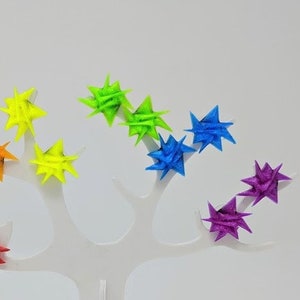 May include: A white tree-shaped earring display stand with colorful star-shaped earrings in red, orange, yellow, green, blue, and purple.