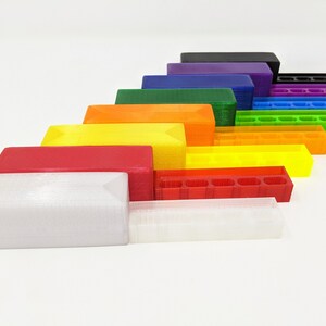 May include: A set of 10 3D printed storage boxes in various colors, including black, purple, green, orange, yellow, red, and white. The boxes are arranged in a rainbow pattern, with the largest box at the bottom and the smallest box at the top.