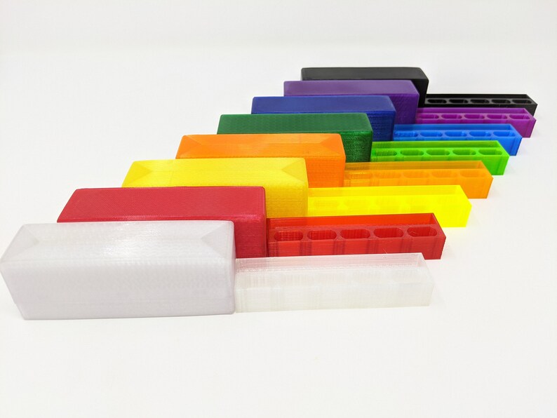 May include: A set of 10 3D printed storage boxes in various colors, including black, purple, green, orange, yellow, red, and white. The boxes are arranged in a rainbow pattern, with the largest box at the bottom and the smallest box at the top.