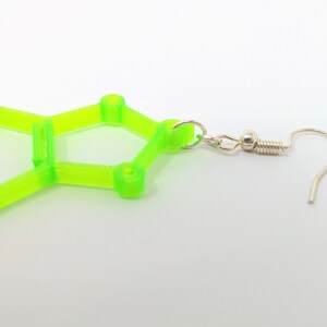 May include: A pair of lime green geometric earrings with a silver hook. The earrings are shaped like a hexagon with a smaller hexagon inside.