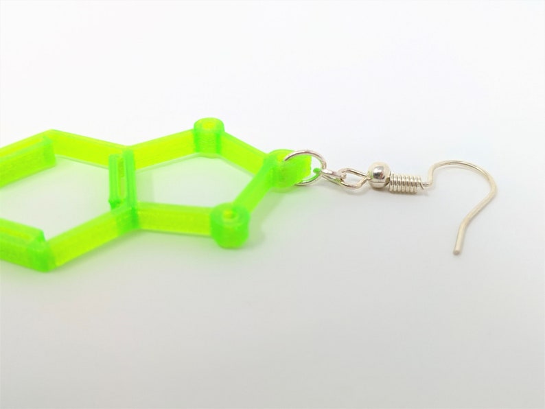 May include: A pair of lime green geometric earrings with a silver hook. The earrings are shaped like a hexagon with a smaller hexagon inside.