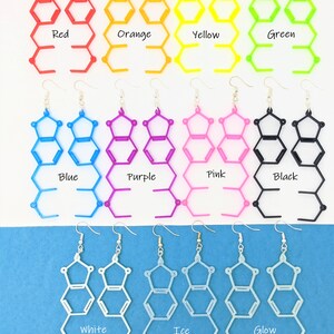 May include: A set of 12 pairs of earrings, each pair featuring a geometric design in a different color. The colors include red, orange, yellow, green, blue, purple, pink, black, white, ice, and glow.