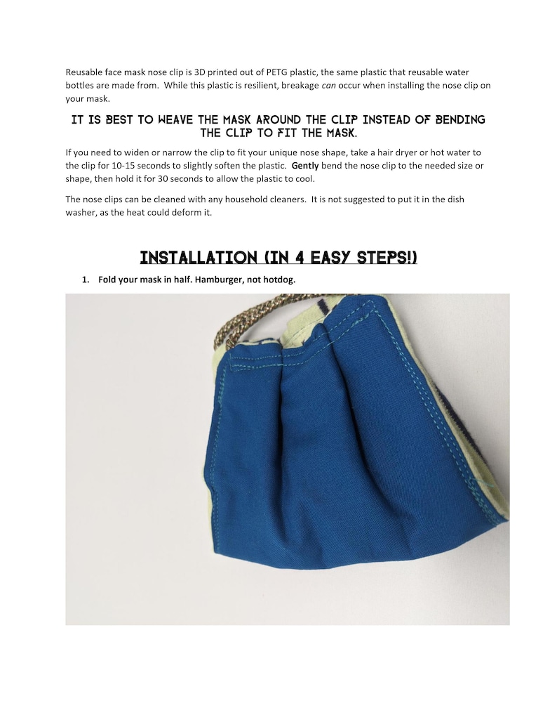 May include: A blue reusable face mask with a white trim. The mask is folded in half, showing the nose clip. The text "IT IS BEST TO WEAVE THE MASK AROUND THE CLIP INSTEAD OF BENDING THE CLIP TO FIT THE MASK." is printed on the page. The text "INSTALLATION (IN 4 EASY STEPS!)" is printed on the page. The text "1. Fold your mask in half. Hamburger, not hotdog." is printed on the page.
