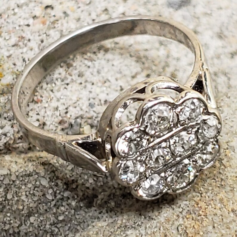May include: A silver ring with a cluster of small diamonds set in a flower-shaped design.