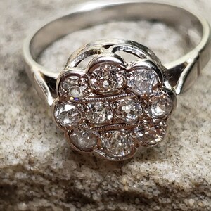 May include: A silver ring with a cluster of small diamonds set in a flower-shaped design.