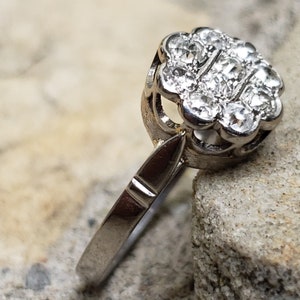 May include: A silver ring with a cluster of small, clear diamonds set in a flower-shaped design.