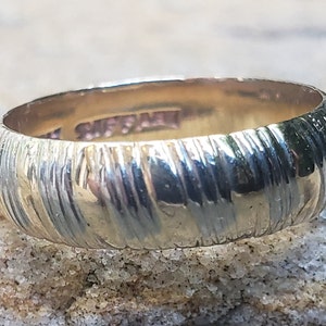 Può includere: Una fede nuziale in oro con un design testurizzato e scanalato. La fascia è lucidata e ha una finitura lucida.