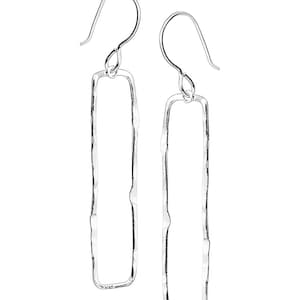 May include: A pair of silver dangle earrings with a rectangular shape. The earrings have a hammered texture and a simple design.